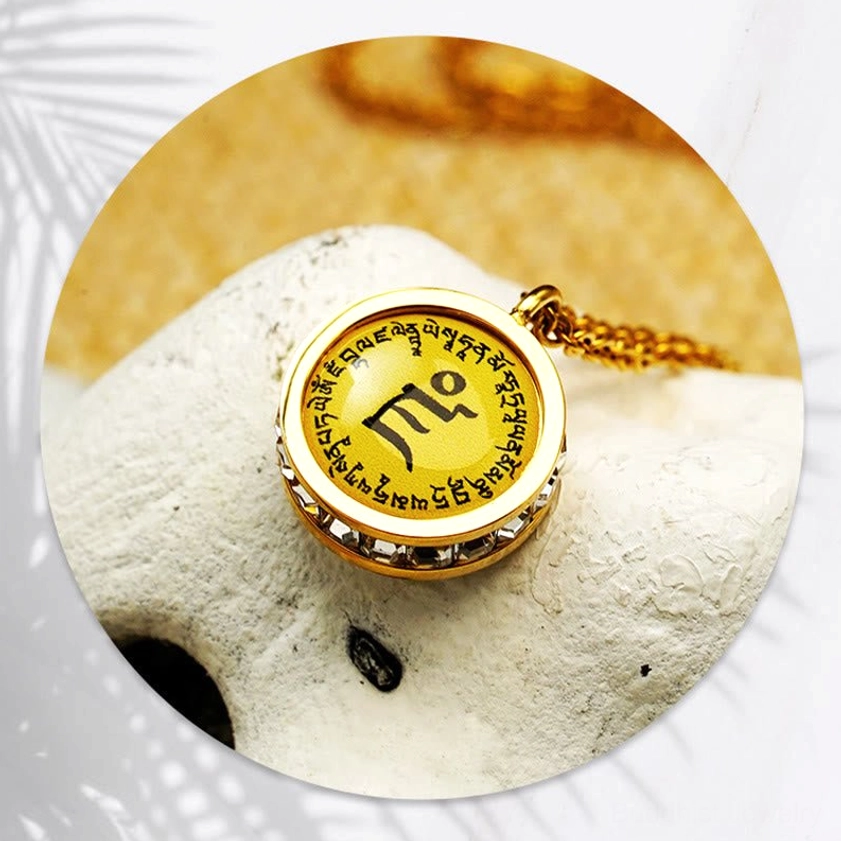 Overhead view of Buddhist mantra pendant - large central sacred text on gold-plated titanium steel