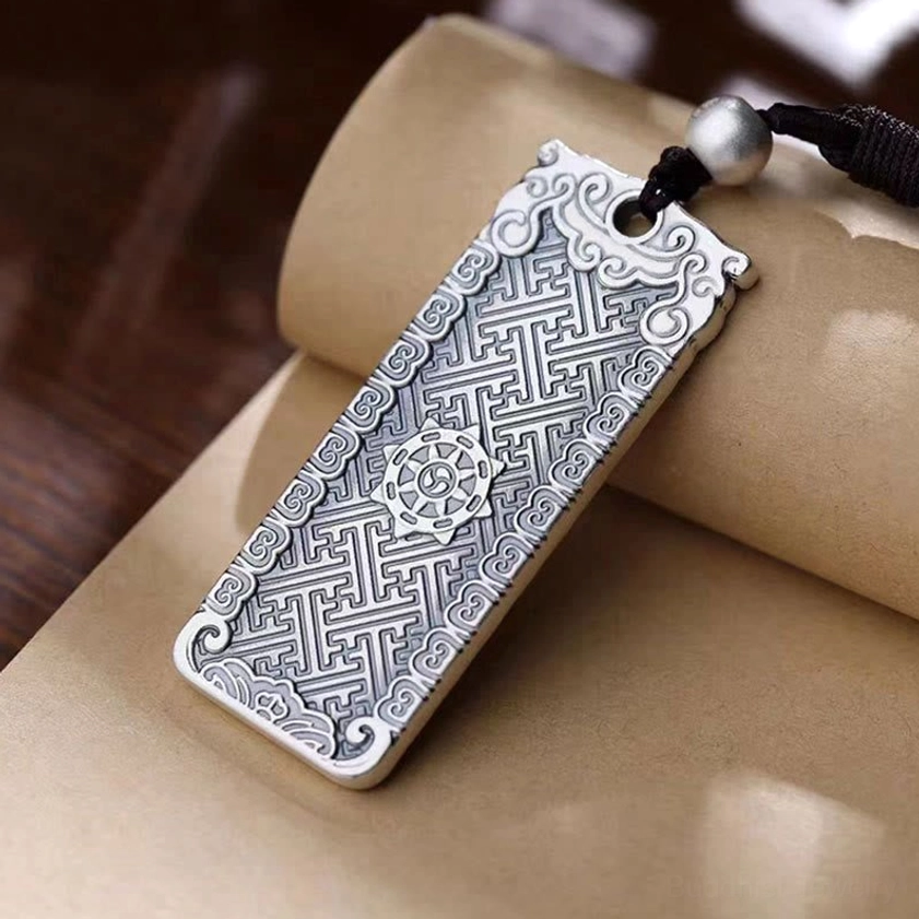 Rectangular Buddhist mantra pendant with engraved Sanskrit text and dharma wheel pattern on antique silver metal