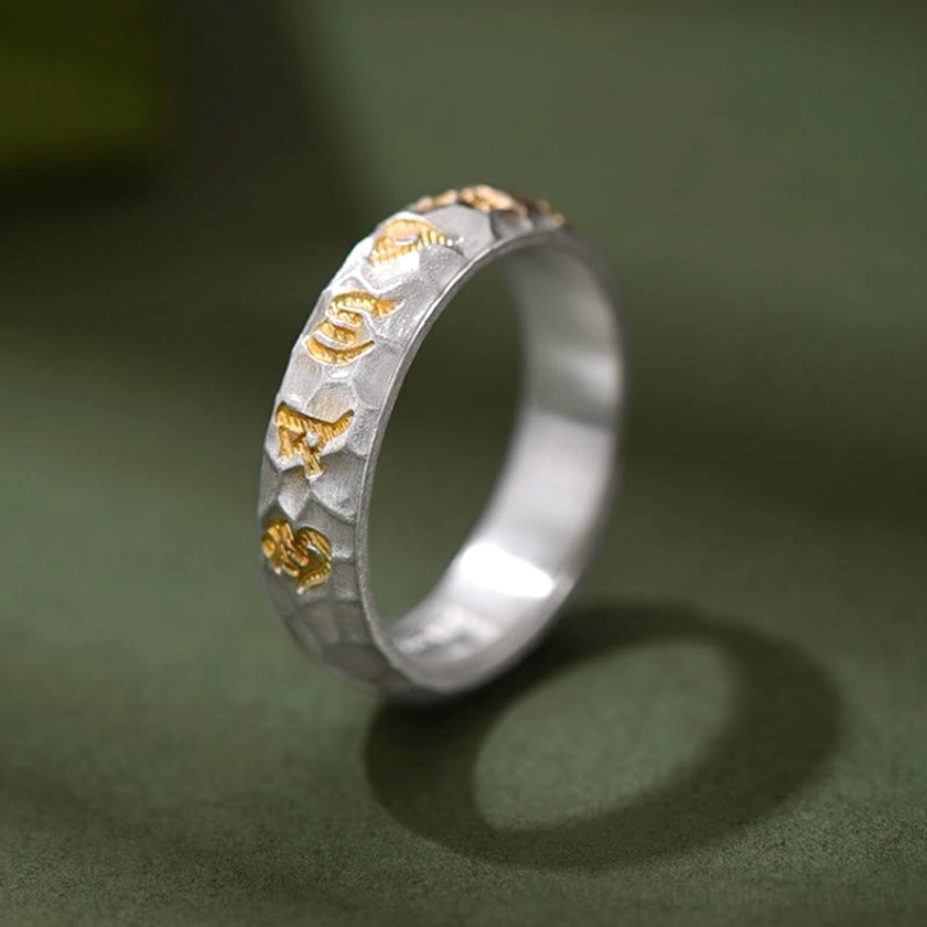 Buddhist mantra ring elevated side angle displaying matte silver base with raised gold Sanskrit text