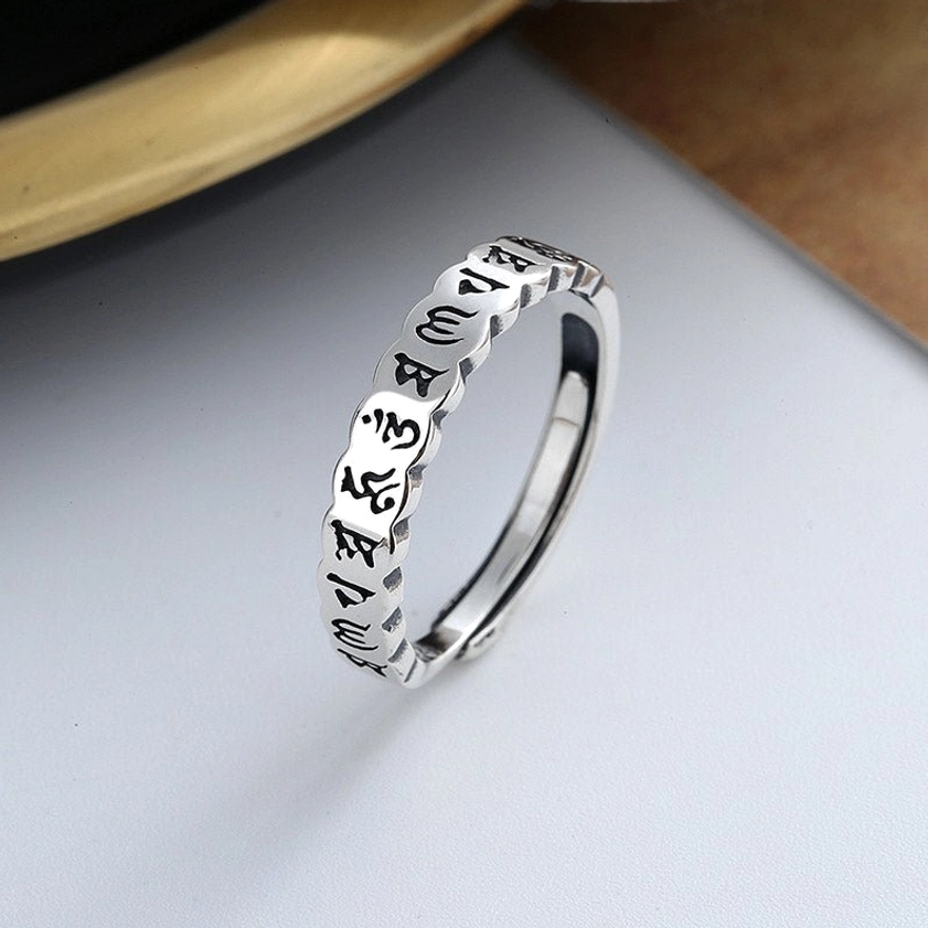 Buddhist mantra ring 925 sterling silver - oblique top view highlighting vintage finish and sacred Sanskrit mantras on light wooden surface