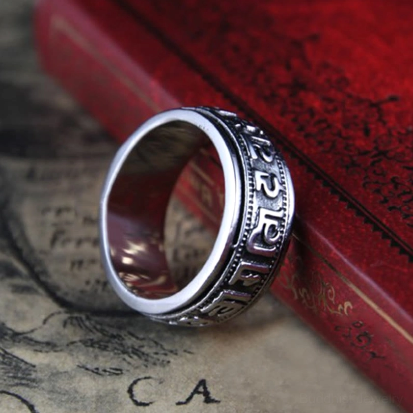 Buddhist mantra spinner ring showing rotatable engraved band and antiqued silver finish, side angle view