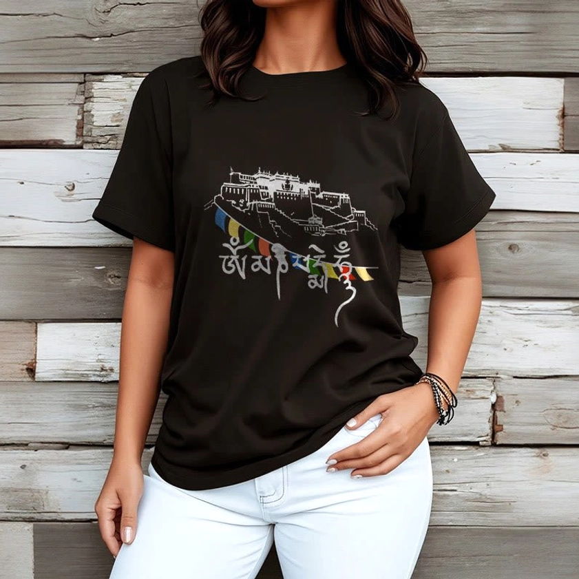 Female model wearing black Buddhist cotton t-shirt with sacred palace and prayer flags print, paired with white pants on wooden background