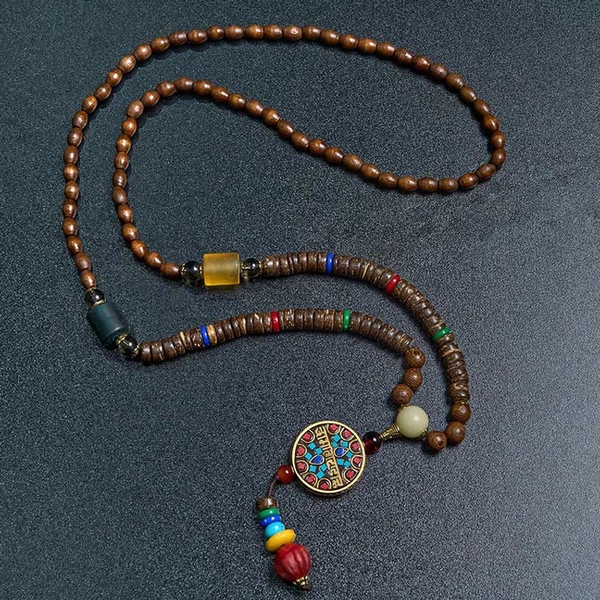 Flat lay of Buddhist prayer necklace with wooden beads and sacred mantra pendant on dark background