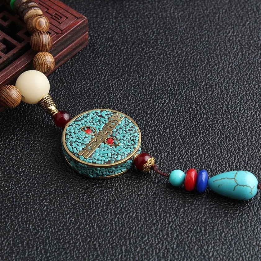 Close-up overhead view of Tibetan Buddhist meditation necklace featuring turquoise pendant and enamel inlay charm with wooden beads