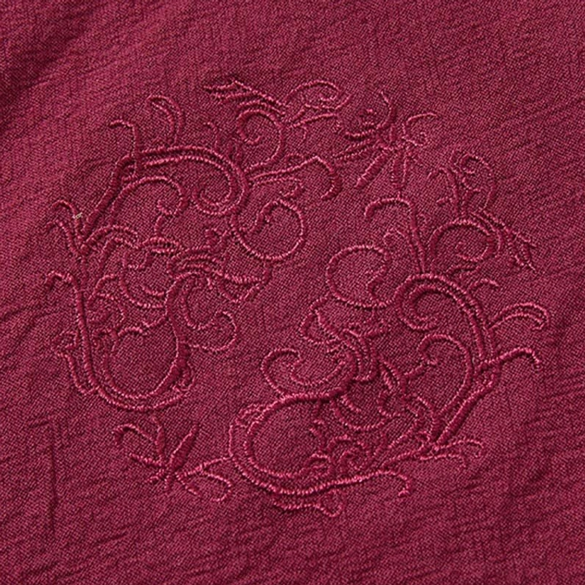 Decorative floral embroidery pattern on burgundy meditation shirt fabric, Eastern spiritual design