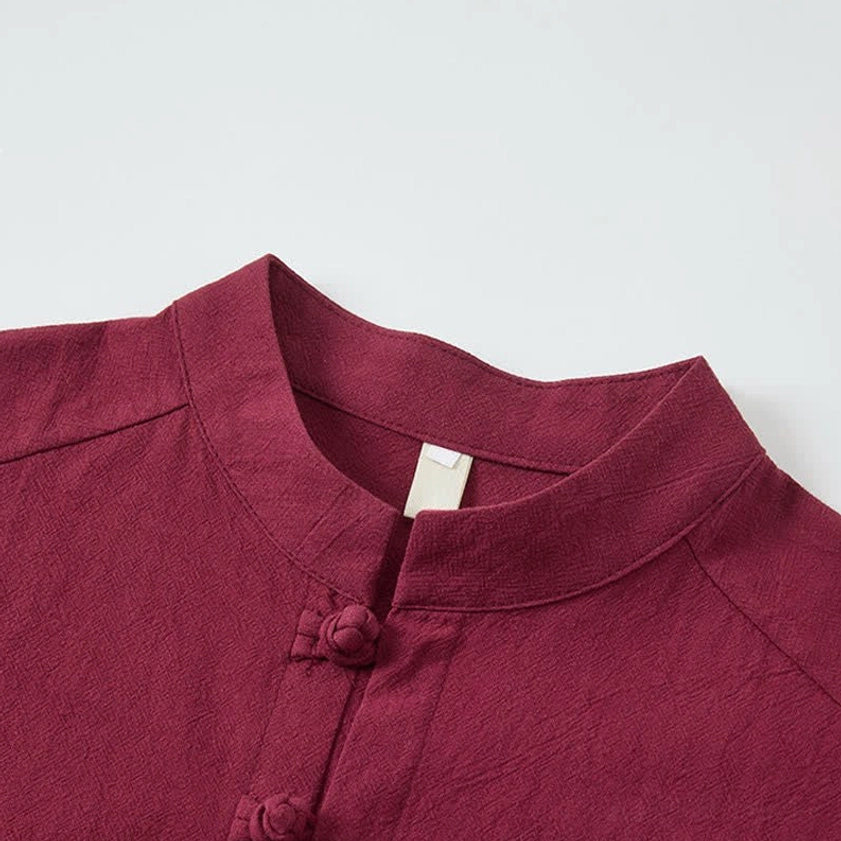 Close-up detail of burgundy mandarin collar with traditional Chinese frog buttons on meditation shirt