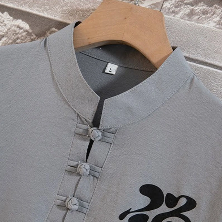 Close-up detail of mandarin collar with traditional frog buttons on Buddhist meditation shirt, showing fine stitching and Zen calligraphy print