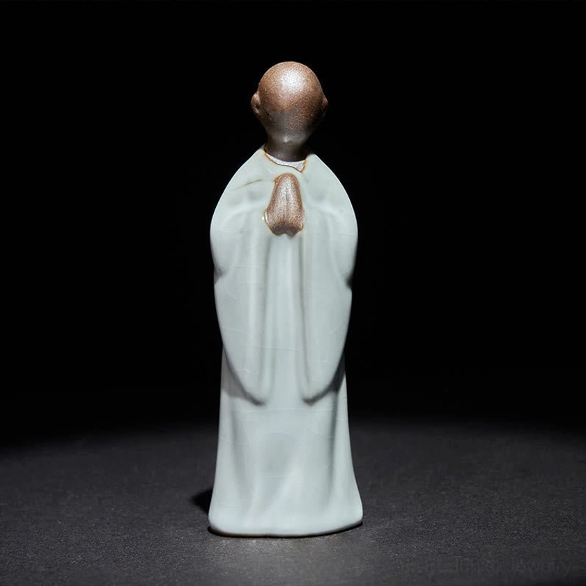 Ceramic meditation monk in traditional praying posture with folded hands spiritual pose