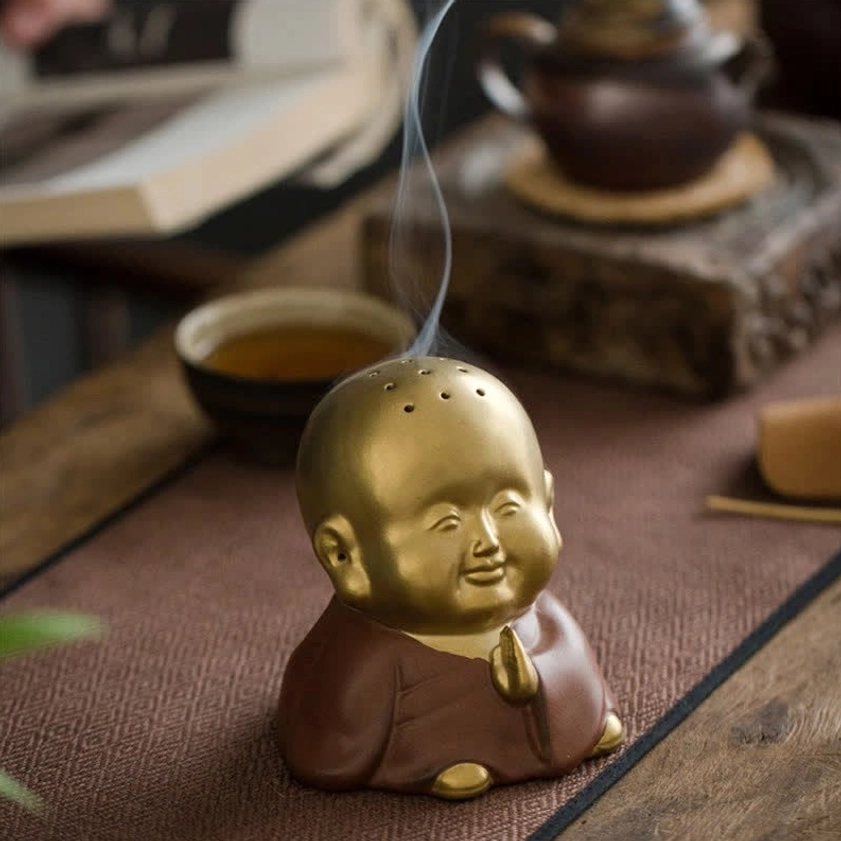 Buddhist monk incense burner three-quarter front view with praying hand detail on traditional tea ceremony setup, incense smoke rising