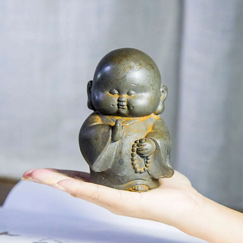 Mini Buddhist monk statue held in adult palm, showing portable size and detailed robe sculpting