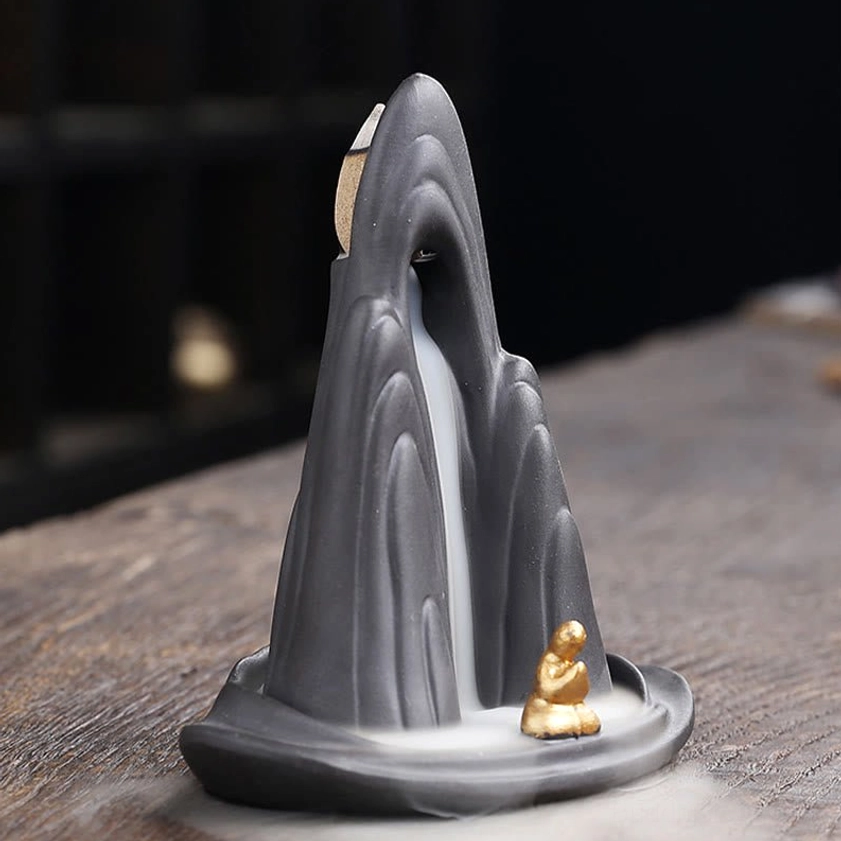Mountain-shaped backflow incense burner with clear smoke cascade and artistic monk placement