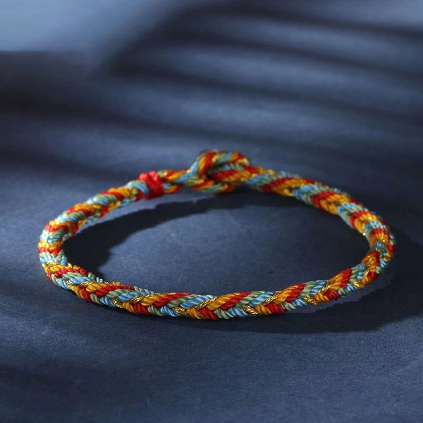 Side profile close-up of handwoven multicolored Buddhist bracelet with silver knot clasp and soft lighting, eye-level angle