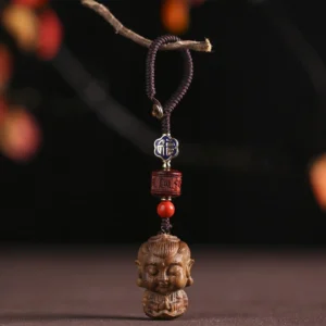 Buddhist Natal Buddha green sandalwood keychain pendant front view with carved Buddha head and woven cord