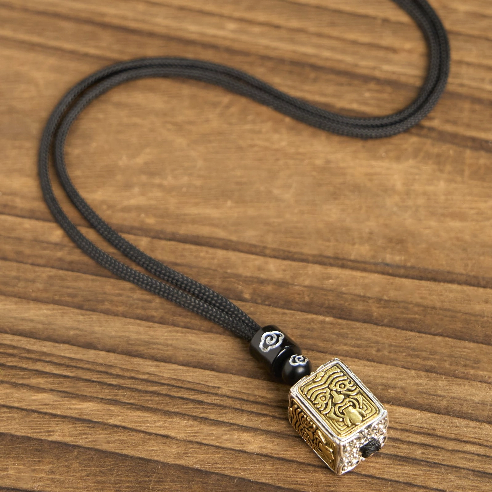 Black braided rope Buddhist necklace with Zakiram pendant and cloud-pattern metal spacer beads, coiled flat