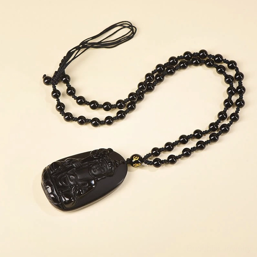 Flat lay view of Buddhist obsidian necklace pendant showing full length and hand-carved Buddha design