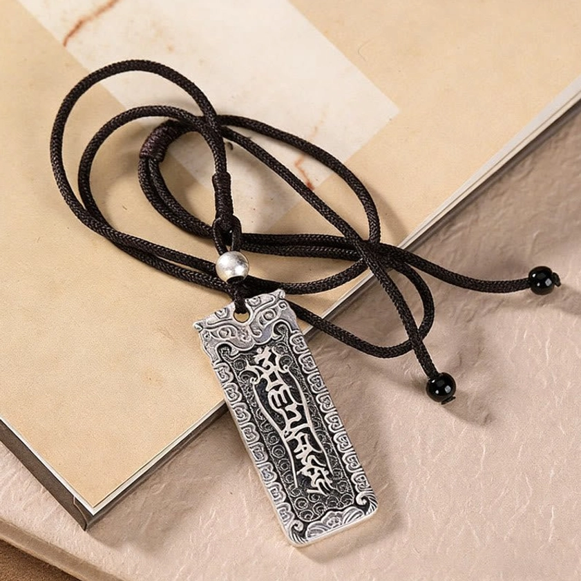 Copper Buddhist six-word mantra Om Mani Padme Hum pendant necklace with black rope and decorative beads on vintage book