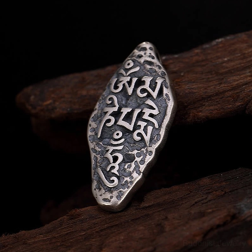 Buddhist mantra Om Mani Padme Hum silver pendant detail showing intricate hand-engraved Vajra symbol and sacred text