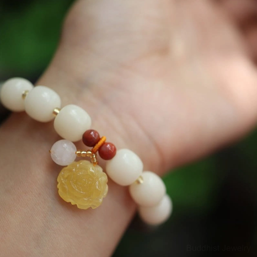 Bodhi seed charm bracelet palm display showing off-white beads with flower pendant and pink accent stones