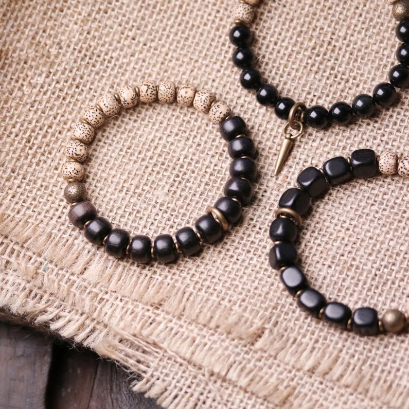 Mixed beaded Buddhist bracelets with bodhi seeds black wood and brass accents on burlap background