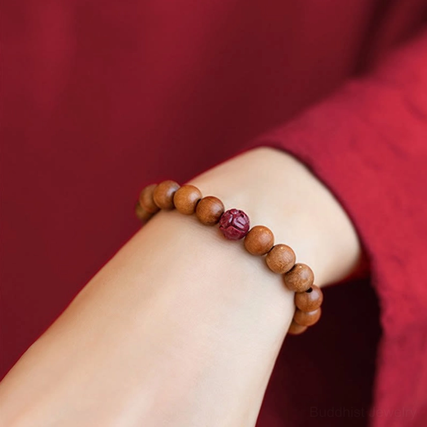 Peach wood and cinnabar lotus bracelet on wrist with neatly arranged natural beads and carved red lotus accent