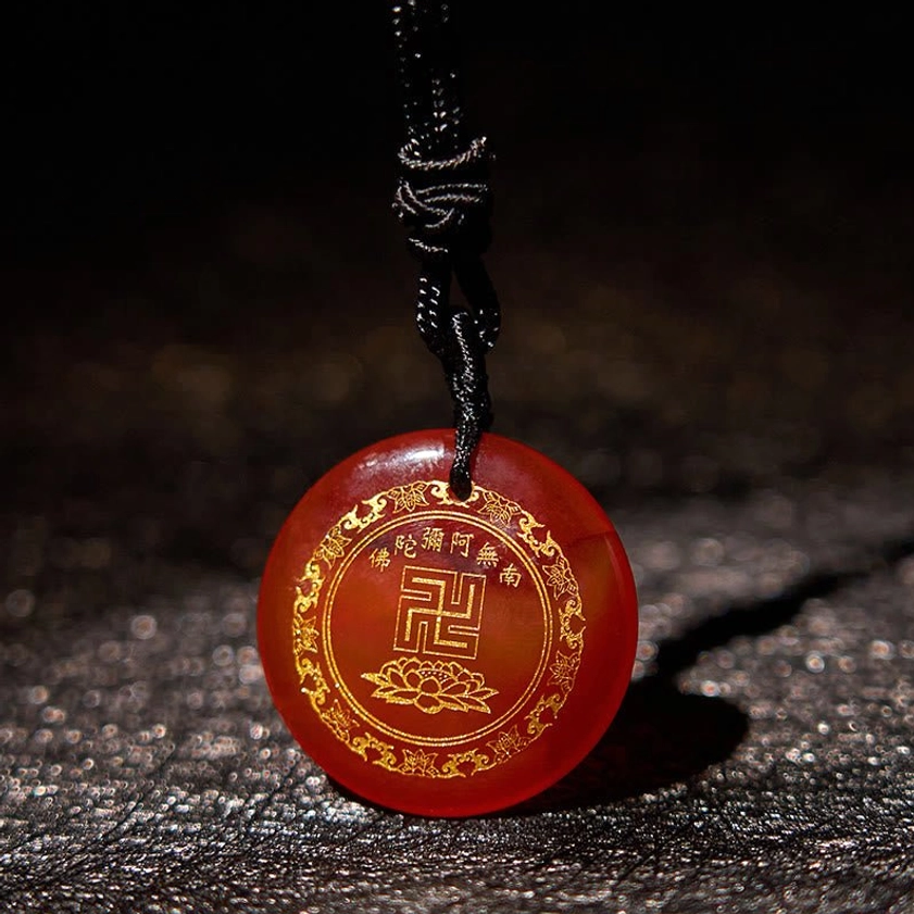 Buddhist pendant necklace close-up detail showing gilded swastika and lotus carving