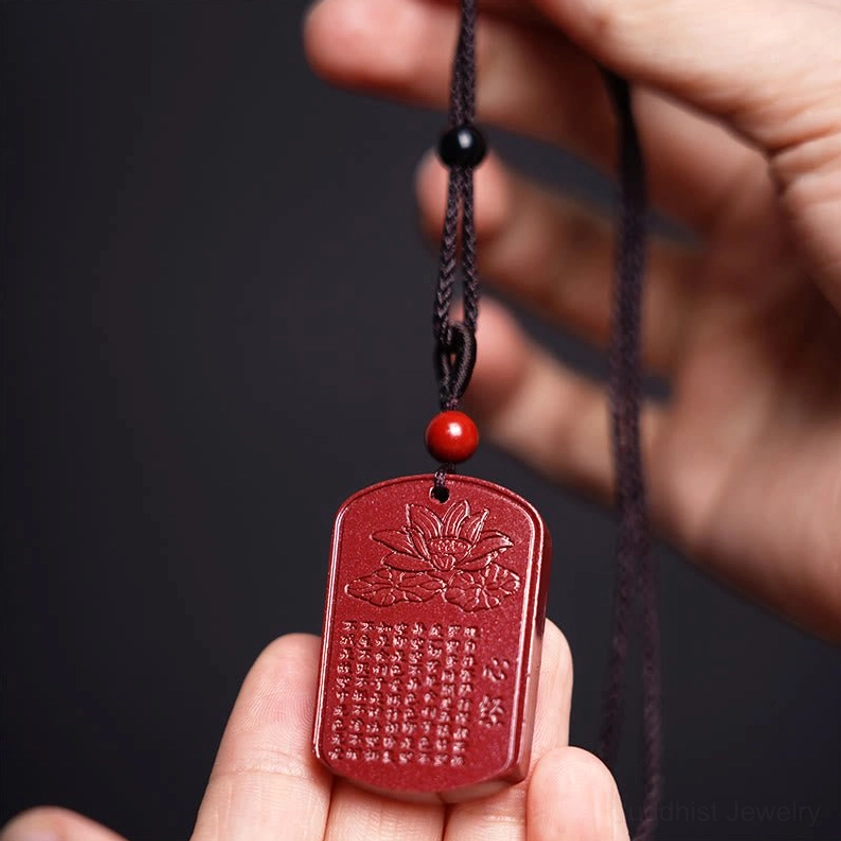 Cinnabar lotus sutra pendant held in hand showing lotus and engraved characters