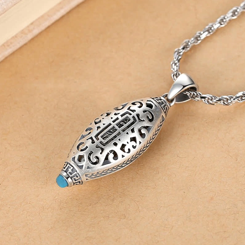 Hollow carved Tibetan Buddhist pendant featuring intricate retro Sanskrit patterns, solid silver tone with blue stone embellishment, side view detail