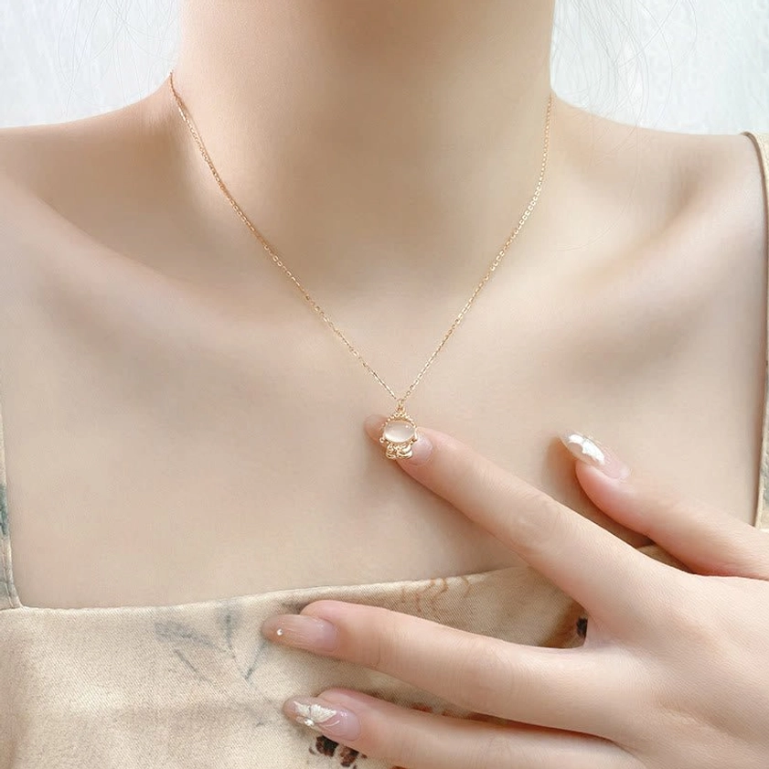 Model wearing delicate chalcedony Buddha pendant necklace on thin silver chain at collarbone, daily wear styling with light clothing backdrop