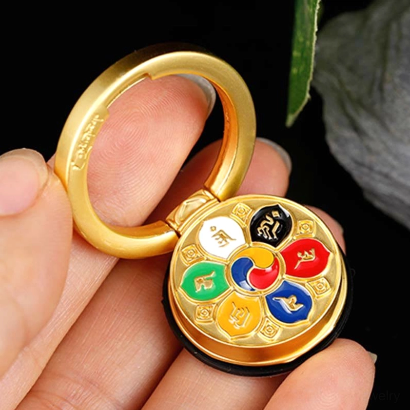 Handheld Om Mani Padme Hum phone ring holder in hand, showing gold-plated metal with enamel patterns and foldable ring design