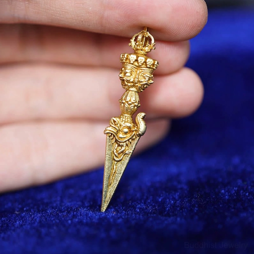 Buddhist phurba amulet with delicate carved patterns and gold finish close-up view