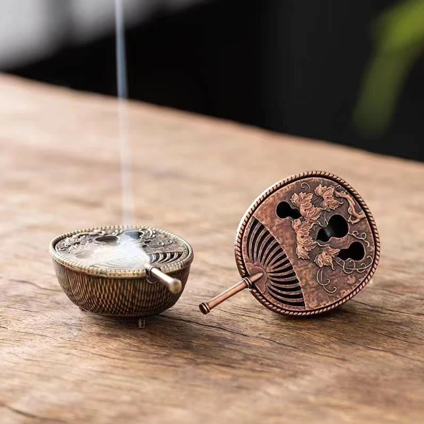 Two Buddhist pipa incense burners displayed on tea table with one burning and releasing fragrant smoke
