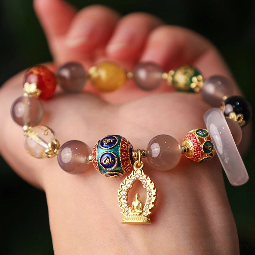 Buddhist beaded bracelet held in palm, showcasing mixed gemstone beads including gray agate, onyx, and enamel decorative elements with Buddha charm