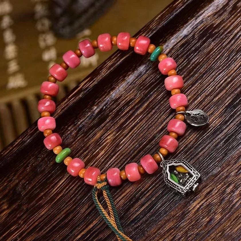 Buddhist prayer bracelet with red agate beads and metal decorative charms top-down perspective