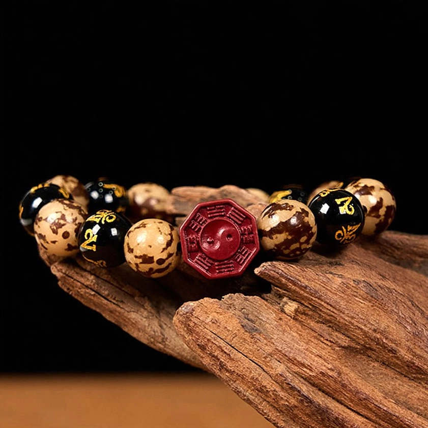 Sacred Buddhist prayer bracelet low side angle showing red cinnabar Bagua charm and tri-color Bodhi bead composition