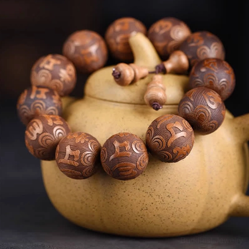 Wooden mantra prayer bracelet displayed on yellow clay teapot with warm brown wood grain visible