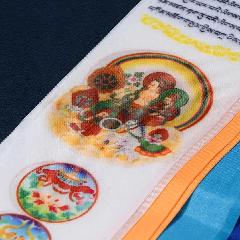 Close-up detail of Buddhist prayer flag surface featuring deity artwork and Tibetan script on silk