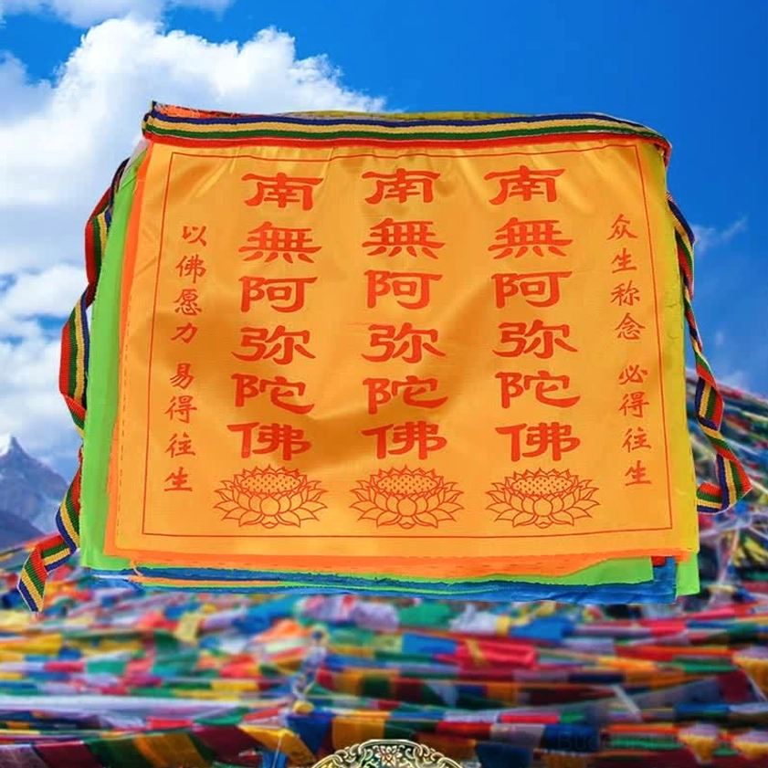 Close-up detail of single Buddhist prayer flag featuring orange satin with lotus patterns and printed mantras against blue sky background