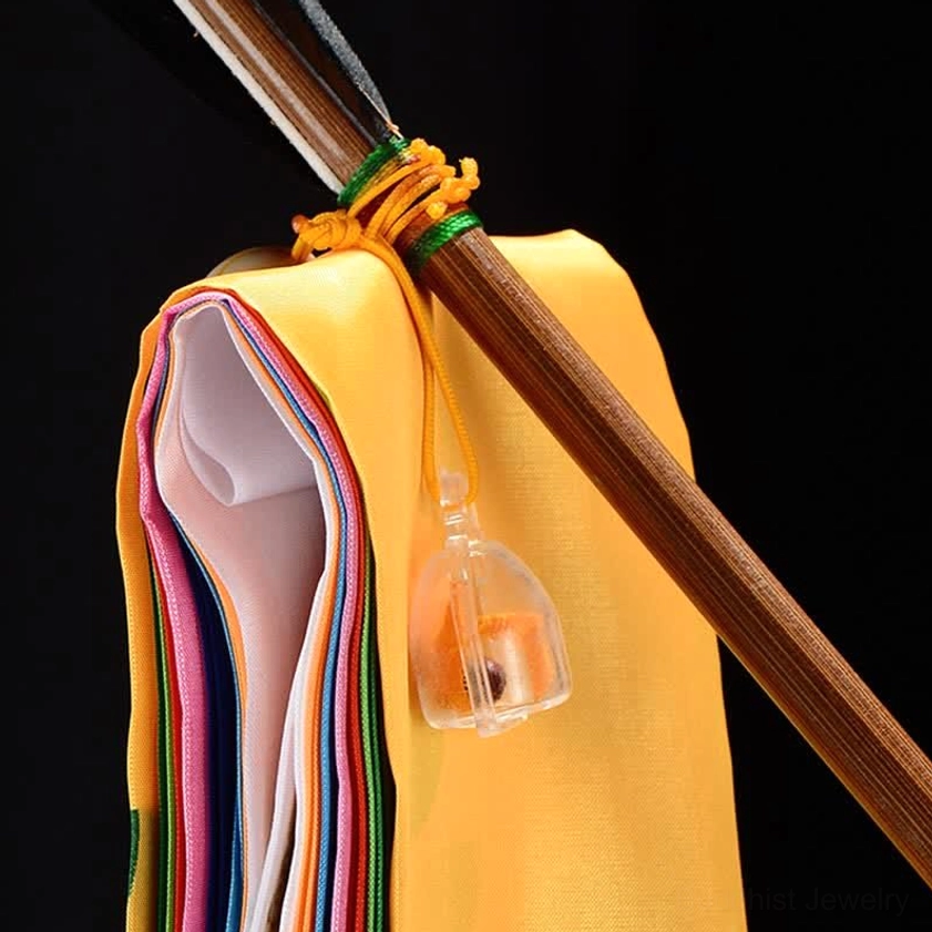 Buddhist prayer flag attached to wooden pole with braided rope fastener and hanging bell