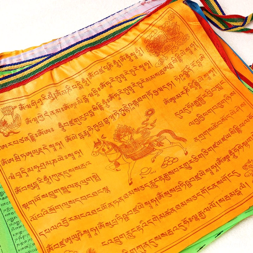 Single Buddhist prayer flag with vibrant orange fabric featuring densely printed Tibetan script, deity on windhorse, and colorful trim borders