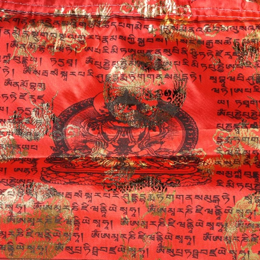 Detailed close-up of red buddhist prayer flag displaying full tibetan sutras and gilded buddha deity print in center
