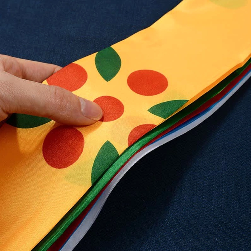 Yellow silk Buddhist prayer flag with red circle and green leaf prints showing layered colorful edges