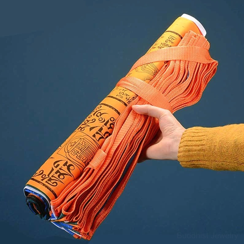 Rolled 25-piece Buddhist prayer flag set held in hand with orange binding strap