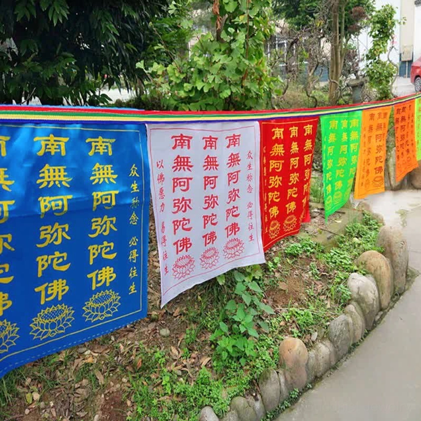 Full set of 5-color Buddhist prayer flags arranged along outdoor pathway, ground-level view showing complete prayer flag banner installation