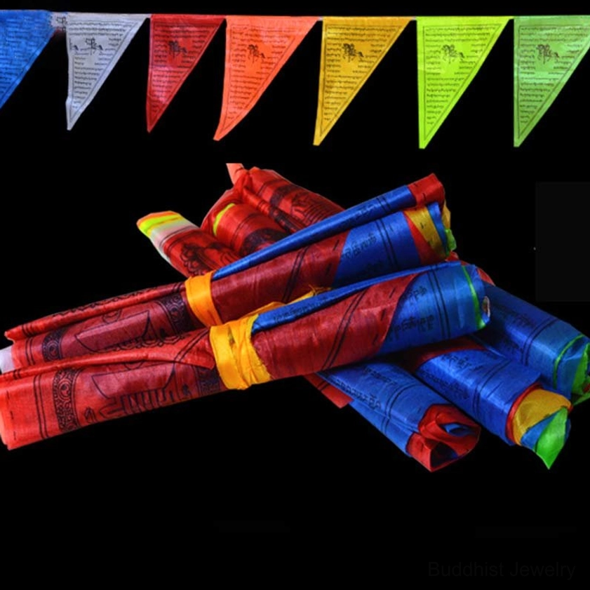 Rolled Buddhist prayer flags bundle wrapped with fabric straps showing vibrant five-color design against black background