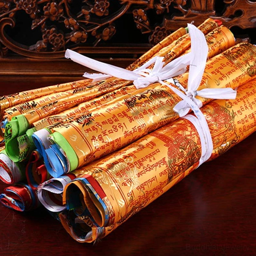 Rolled buddhist prayer flags bundle with golden fabric and red sutra patterns tied with white cord on carved wooden table