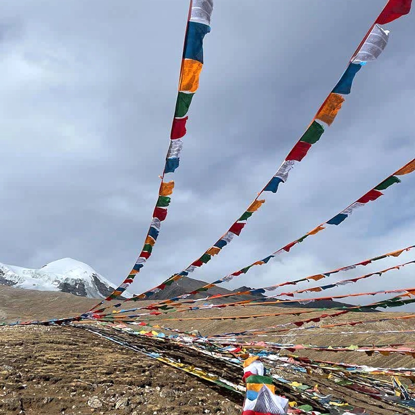 Buddhist prayer flags fluttering in wind at snow-capped mountain highland altitude