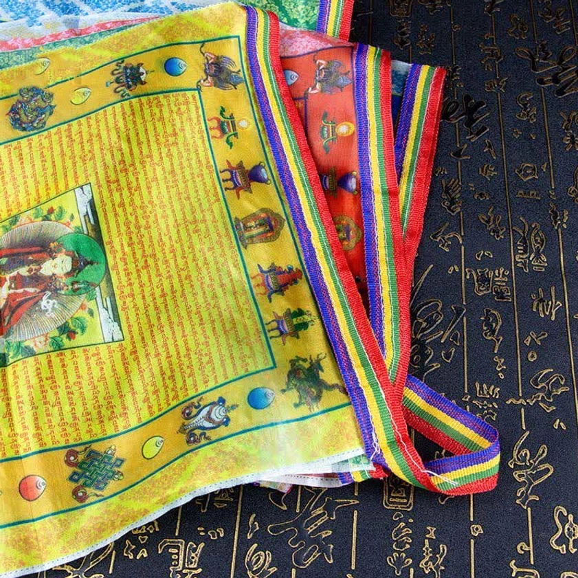 Stack of yellow Buddhist prayer flags with Padmasambhava portrait and colorful woven edge straps visible