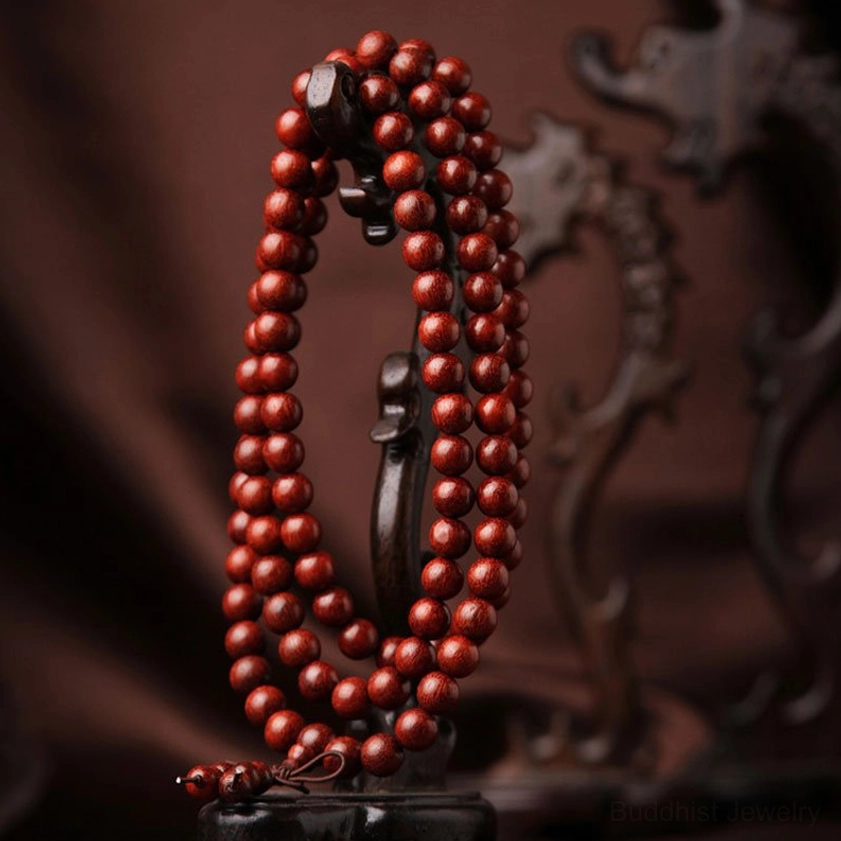 Authentic red sandalwood prayer mala hanging from traditional carved wooden display rack showing smooth wooden beads