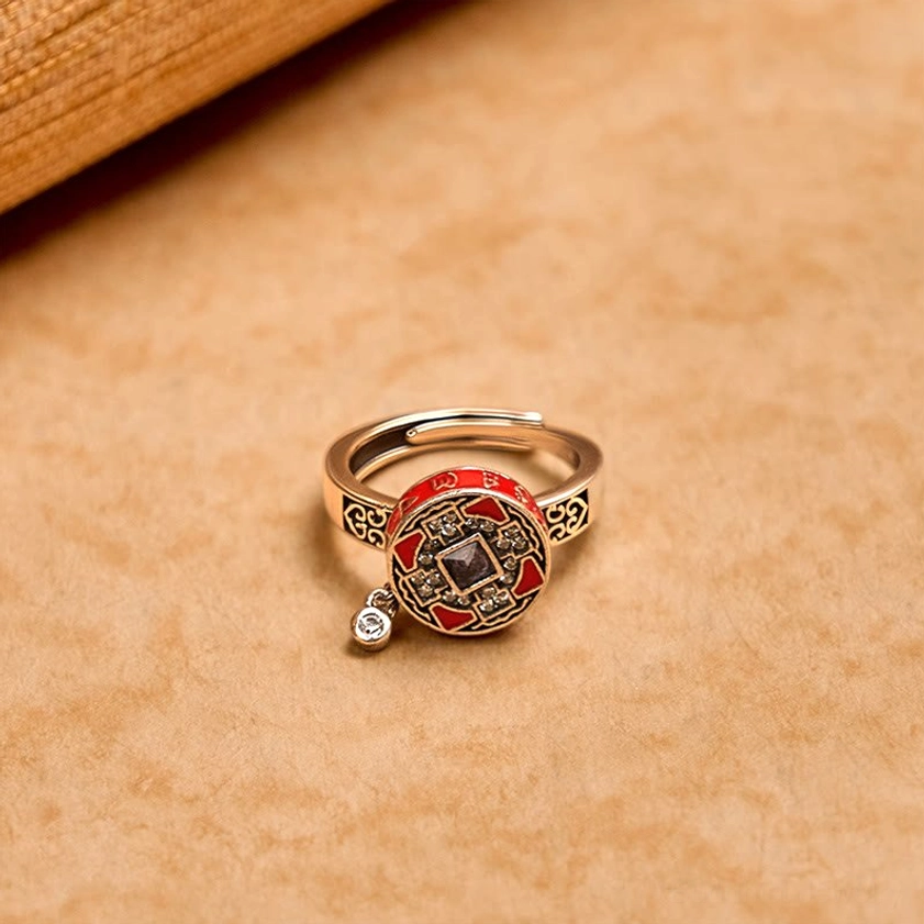 Adjustable Buddhist prayer ring side view showing rotatable red enamel top with dual-tone metal and crystal accent