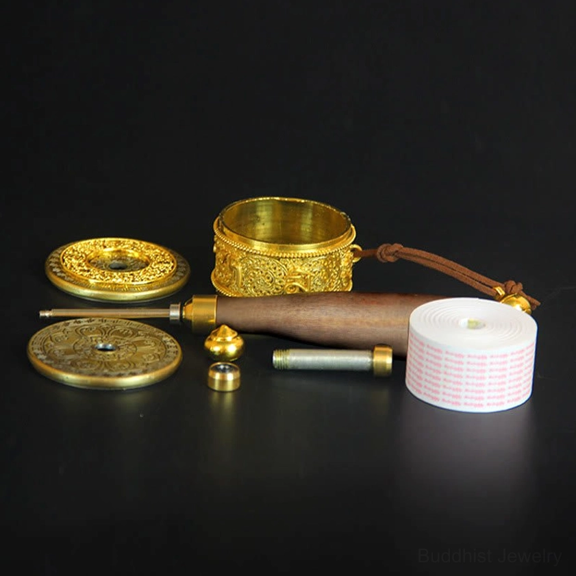 Disassembled Buddhist prayer wheel components showing copper body, metal parts, wooden handle, and assembly elements